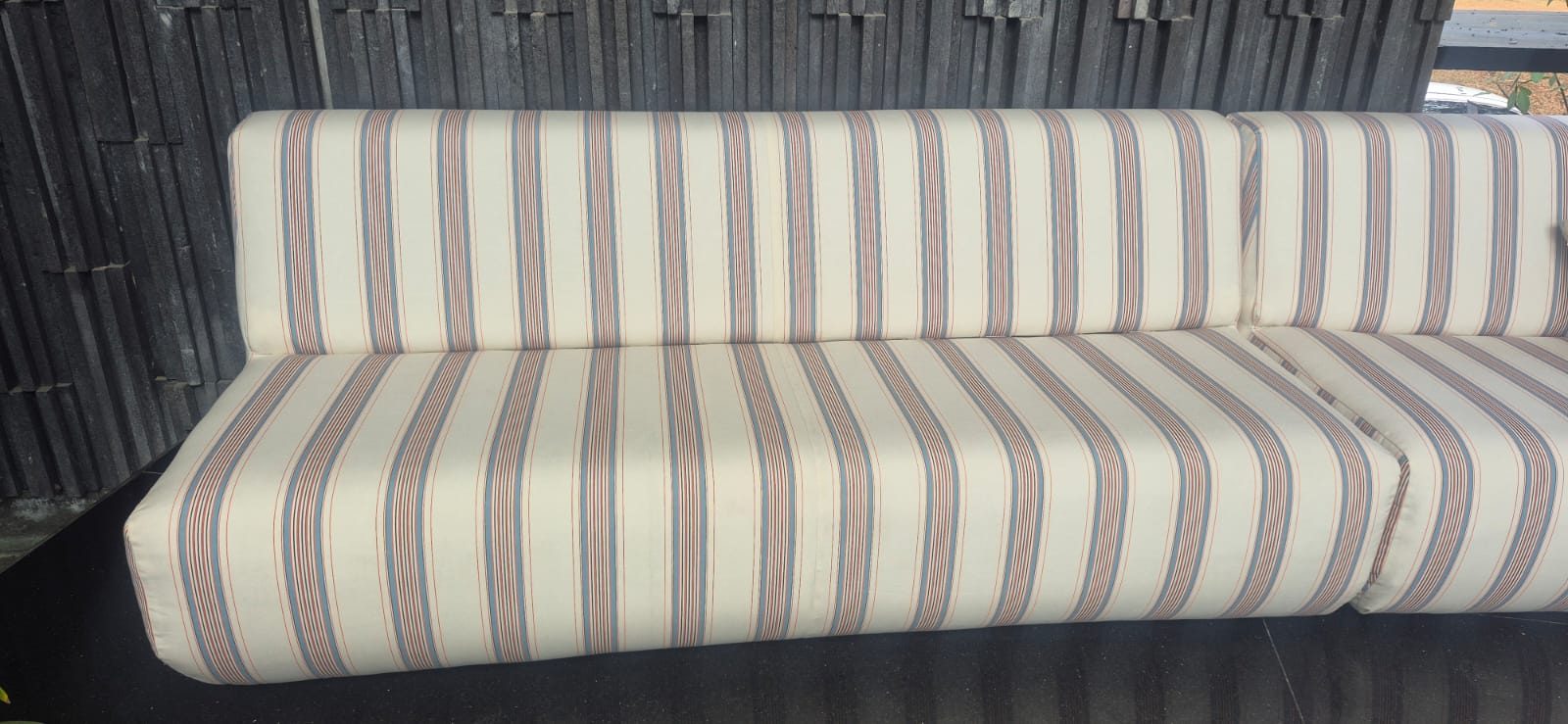 Pengerjaan upholstery sofa dengan motif garis vertikal warna netral (krem, biru, dan merah marun) yang mengoptimalkan kenyamanan duduk, kehangatan area santai, dan keunikan visual furnitur.